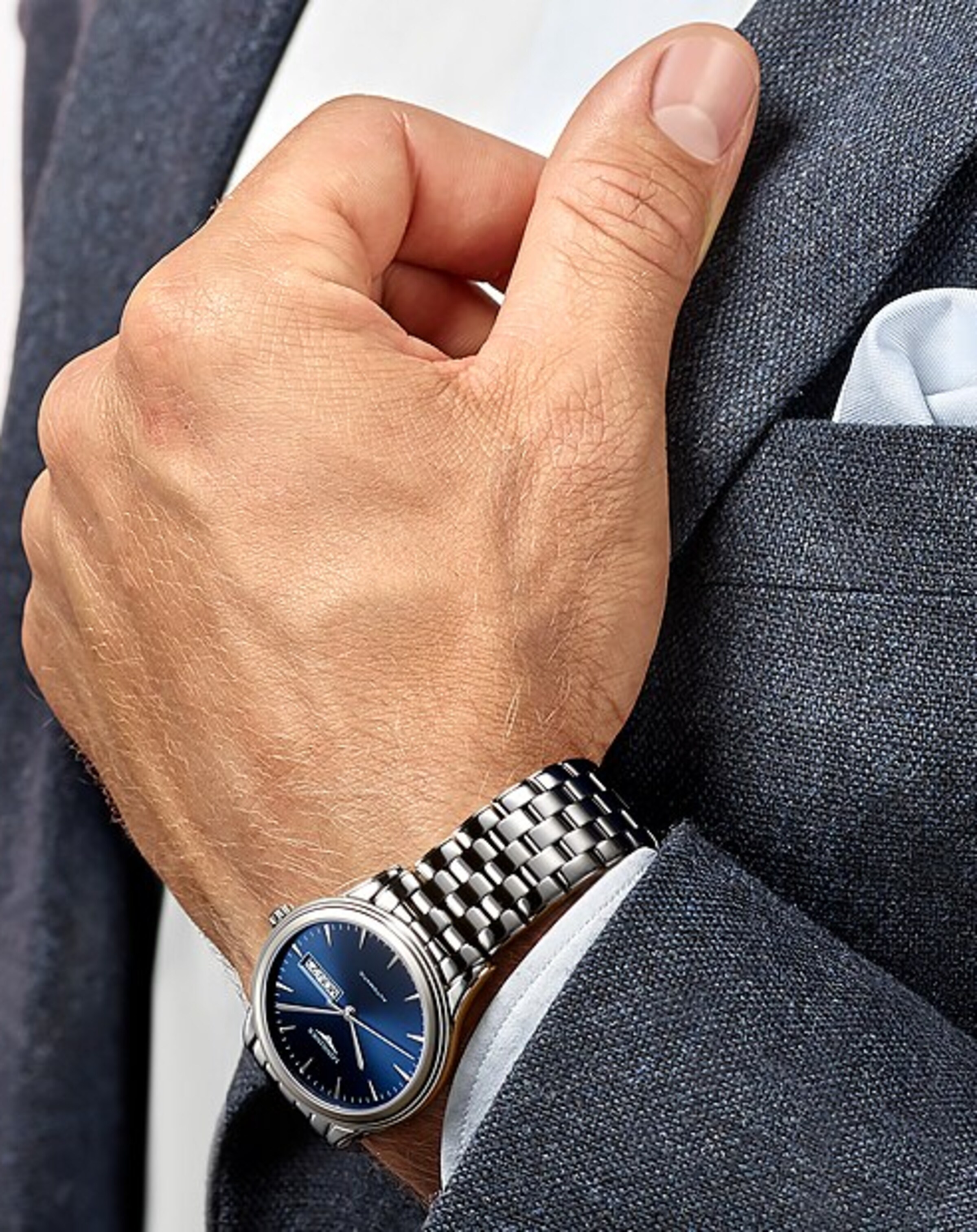 a man in suit is wearing a Longines watch