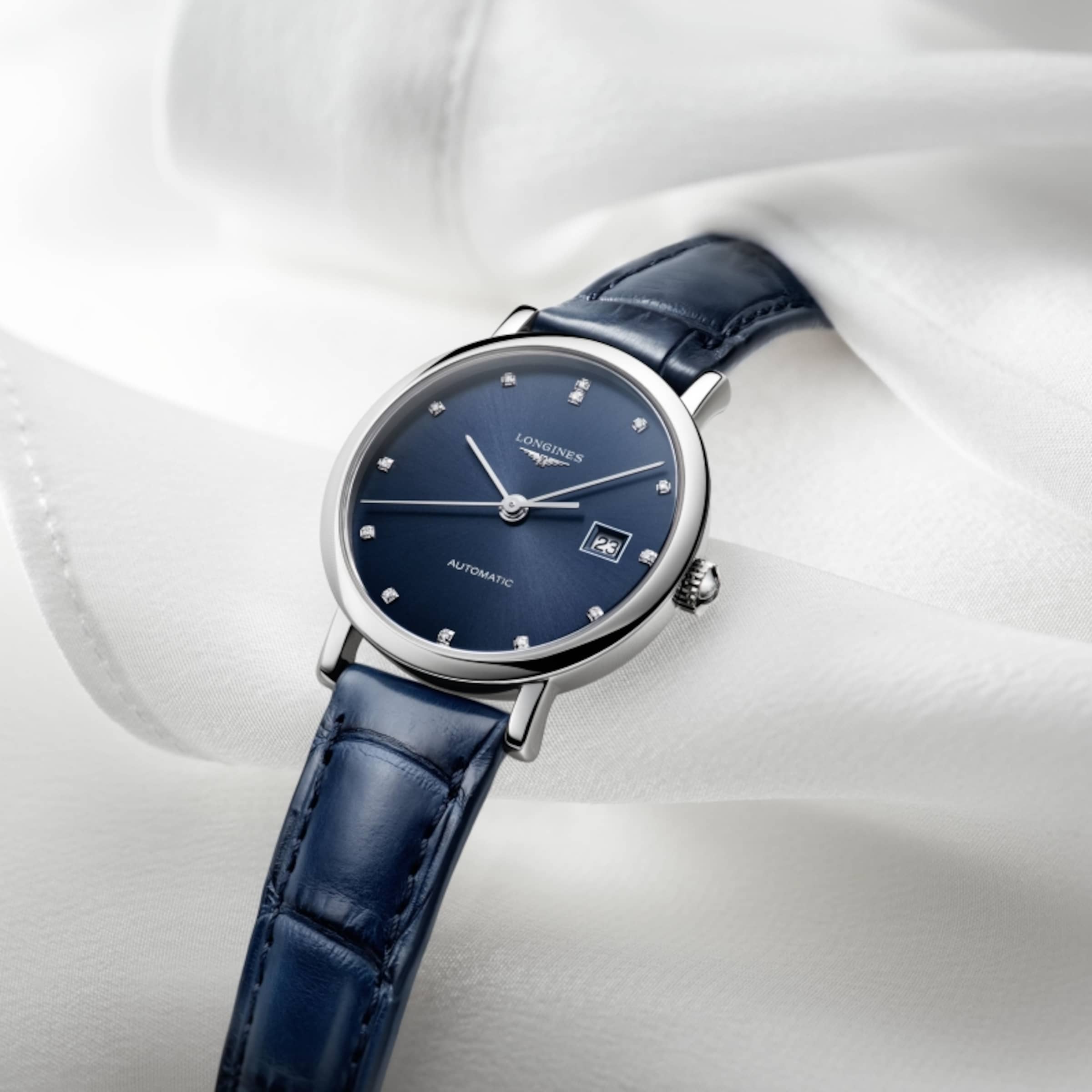 A blue model of The Longines Elegant Collection watch on a white fabric